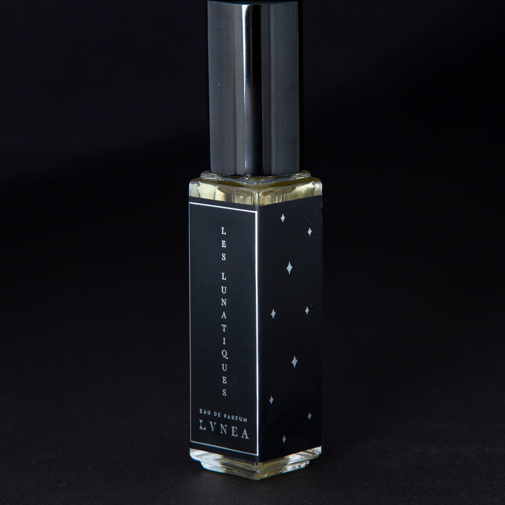 
                      
                        8ml clear glass bottle of LVNEA’s Les Lunatiques natural perfume on black background, bottle is rotated at a 3/4 angle exposing a star pattern on the label.
                      
                    