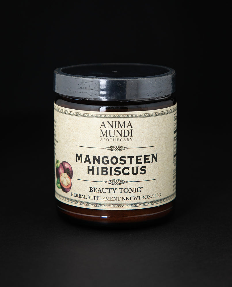 Amber glass jar of Anima Mundi's "Mangosteen Hibiscus" herbal supplement. The tan label reads "Beauty tonic"