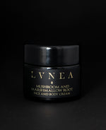 A moisturizing and skin-protecting botanical face and body cream by LVNEA housed in a 50ml black glass jar. The label reads "MUSHROOM AND MARSHMALLOW ROOT FACE AND BODY CREAM" in gold.