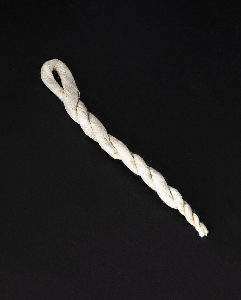 A single unit of rope incense on a black background. Each piece consists of botanical material wrapped in paper and twisted.