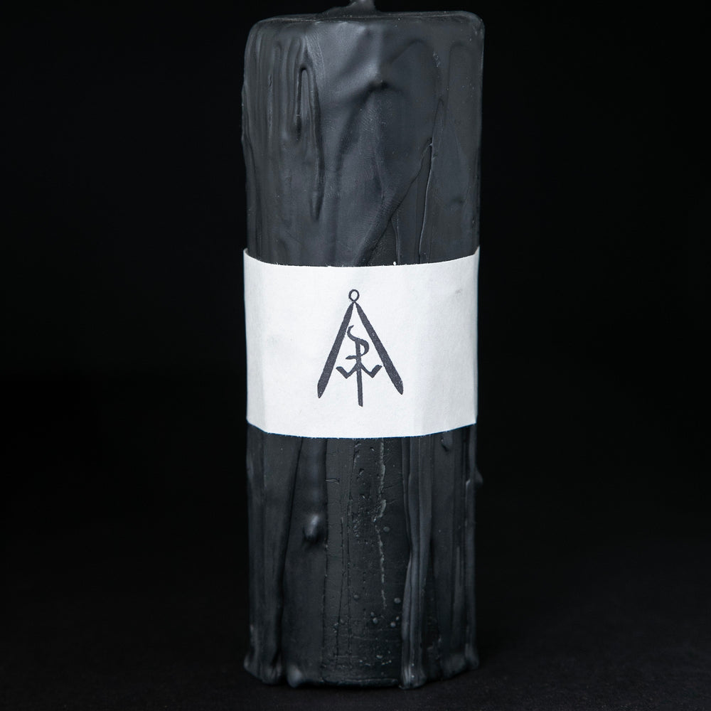 Tall black beeswax pillar candle by RITUAALIA on black background. The candle has a rustic textured finish with visible drips.