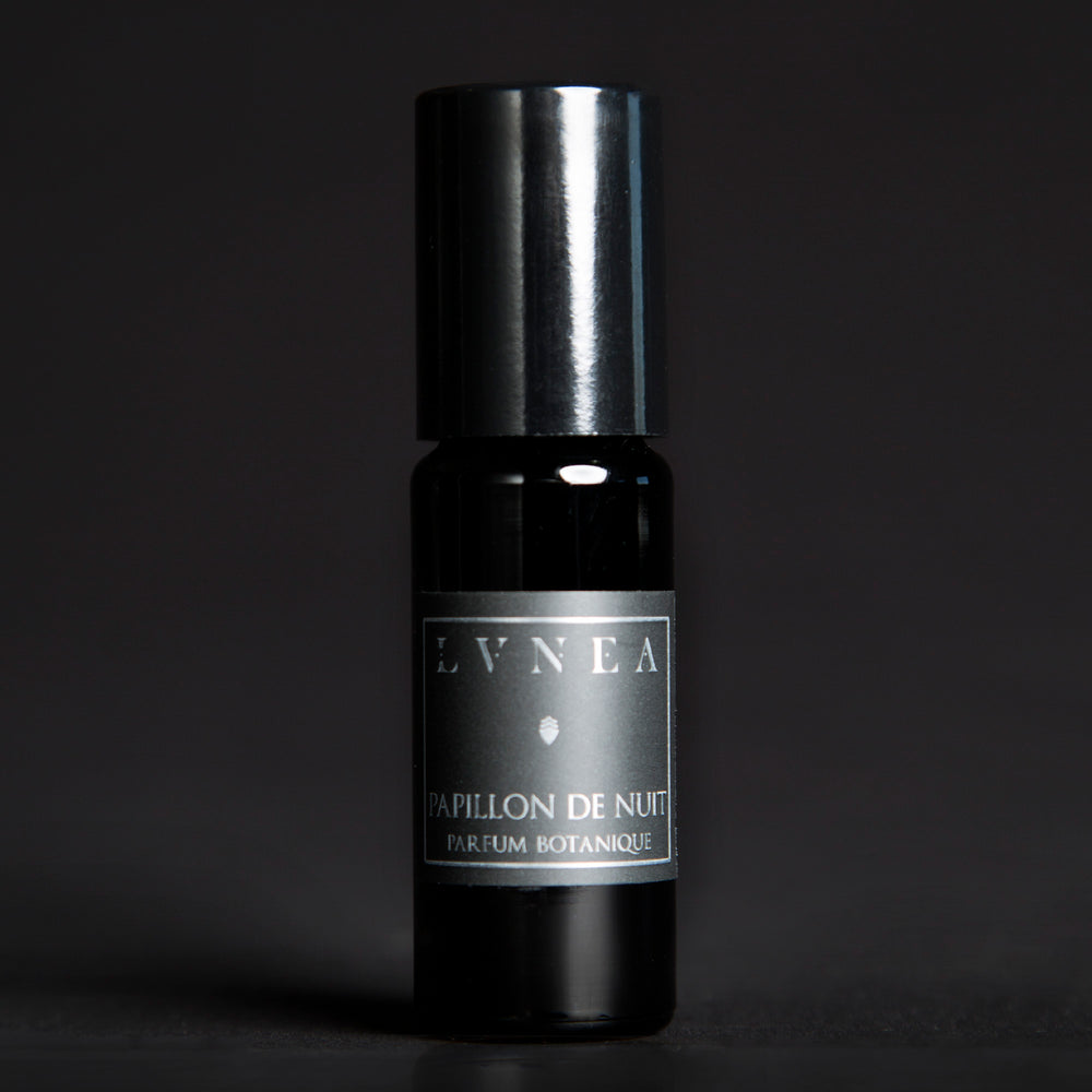 10ml black glass bottle of LVNEA's Papillon de Nuit natural roll on perfume oil on black background