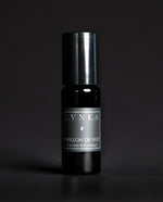 10ml black glass bottle of LVNEA's Papillon de Nuit natural roll on perfume oil on black background