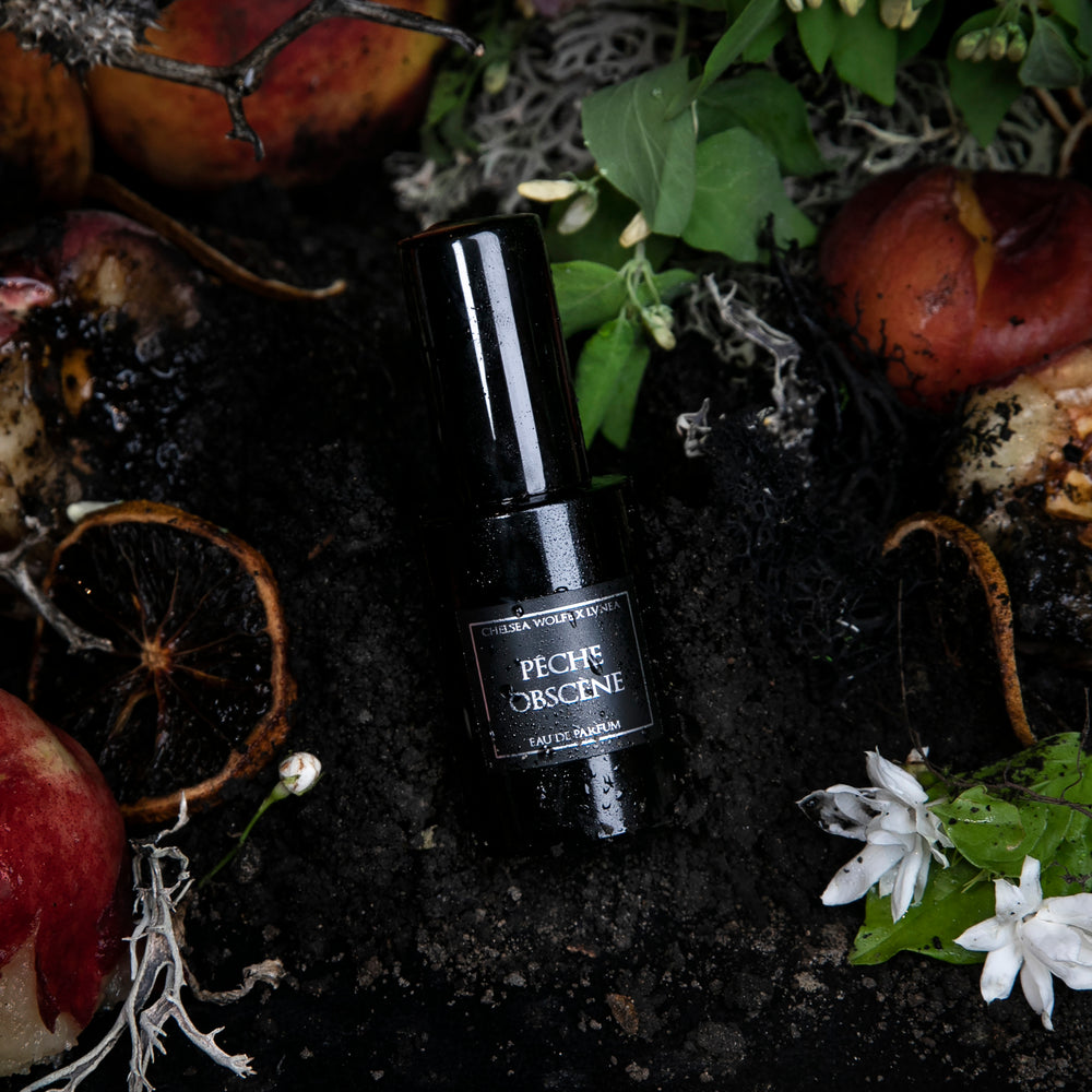 
                      
                        30ml black glass bottle of LVNEA best-selling natural perfume Peche Obscene lying on dirt surrounded by ripe peaches, jasmine, and botanicals
                      
                    