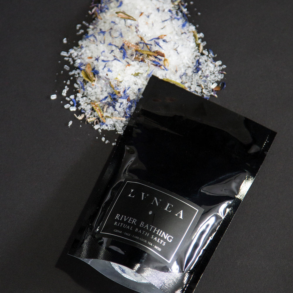 4oz black resealable pouch of LVNEA's River Bathing bath salts with a mound of salt next to it