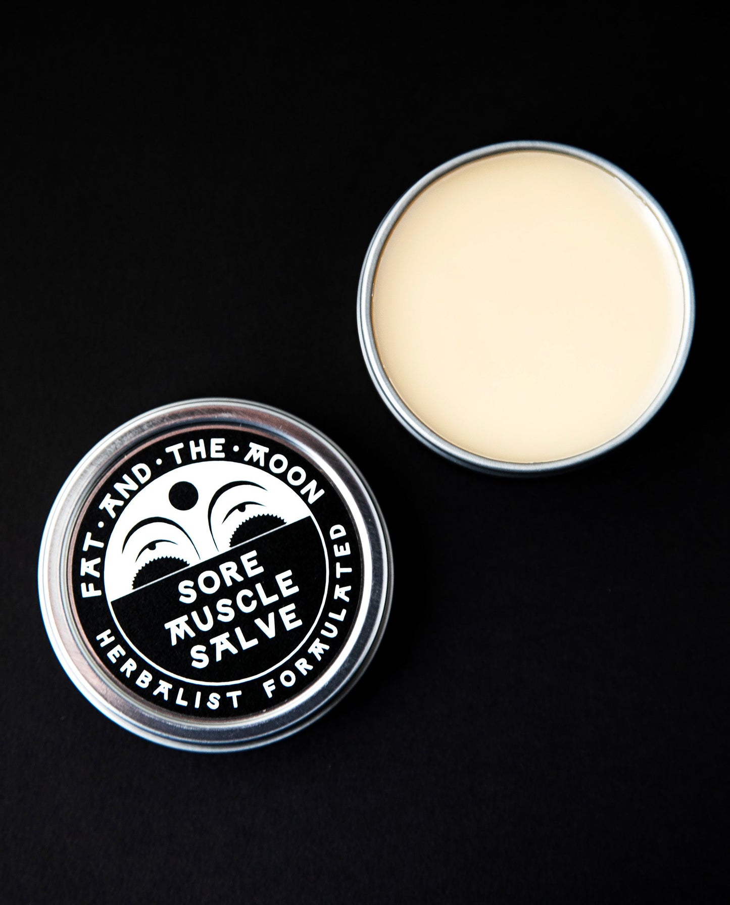 Metal tin with lid removed, revealing a white salve within the tin.