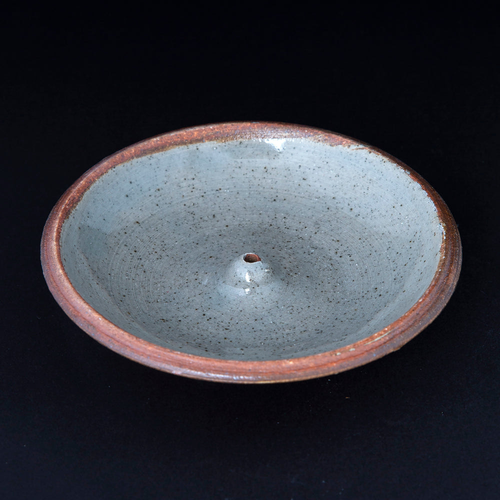 speckled grey glazed stoneware incense holder on black background