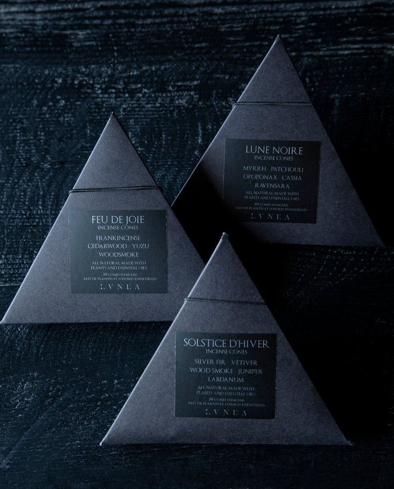 A set of three boxes of LVNEA incense cones. Each contains 20 cones housed in a recyclable black paper pyramid box with a black elastic closure. The labels are black with silver lettering each respectively describing the products as follows Solstice d'hiver features vetiver, woodsmoke, silver fir, labdanum, and juniper. Lune Noire myrrh, patchouli, opoponax, cassia and ravensara. Feu de joie features of frankincense, cedarwood, yuzu, and woodsmoke.